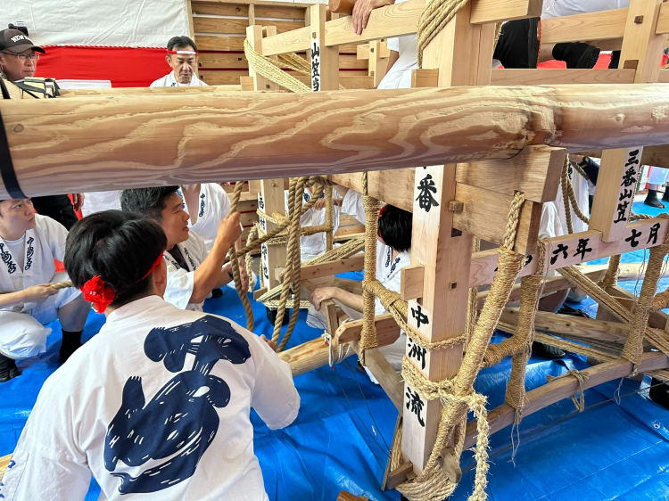 6月26日由穿着中州流统一的“水法被”的参加者在山笠台上设置抬杠，进行“绑杠”